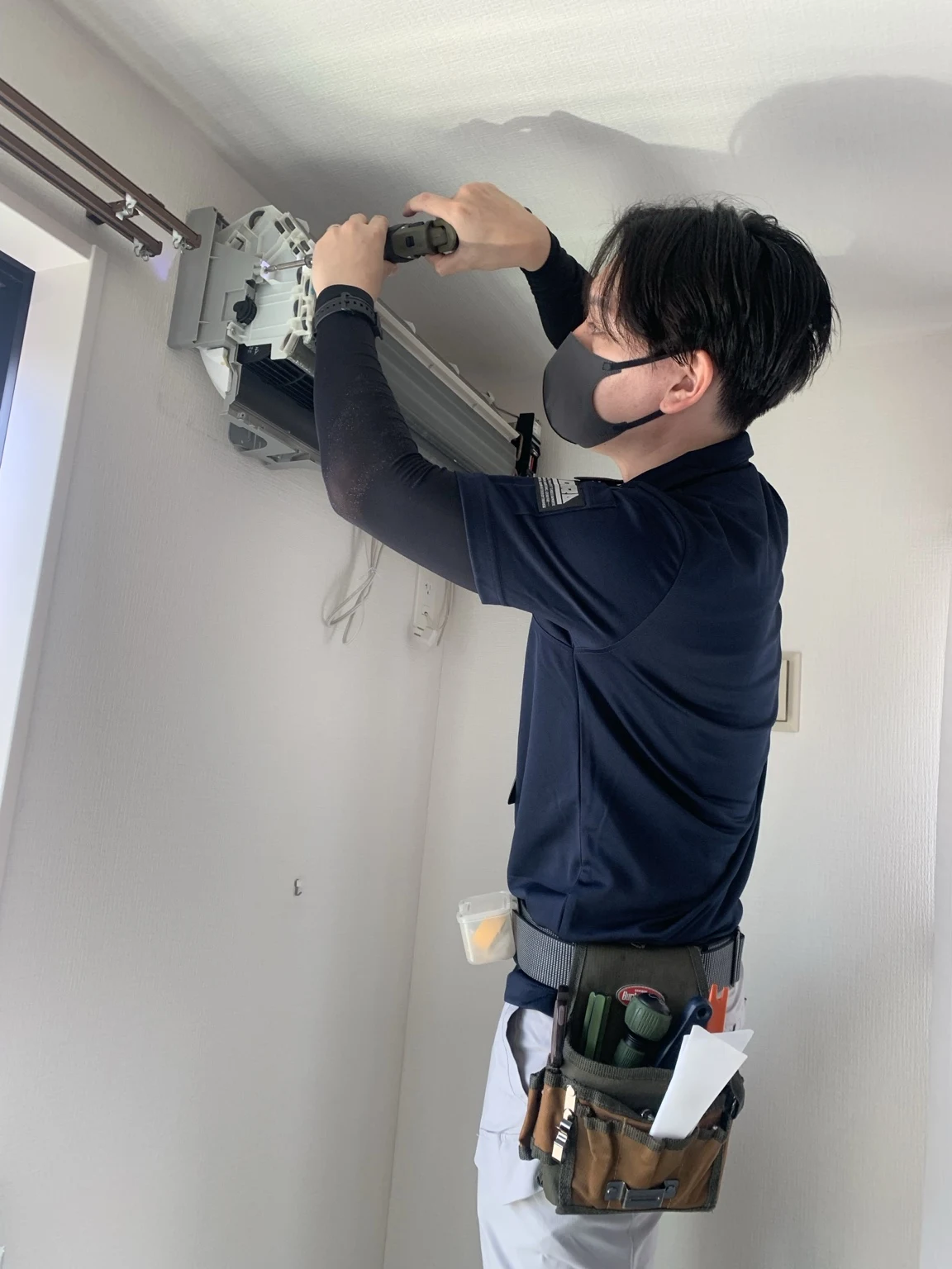 エアコンの内部パーツを丁寧に取り外す作業風景